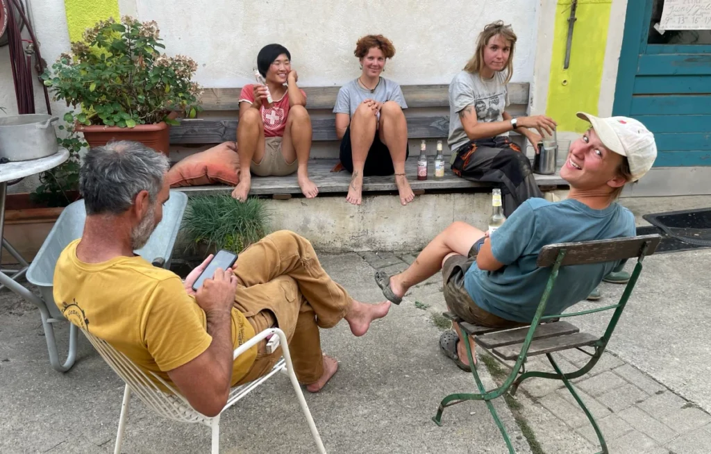 Verdiente Erholung: Das Gartenteam der Solawi Luzernenhof genießt eine entspannte Pause im Innenhof – barfuß und gut gelaunt nach der Arbeit.