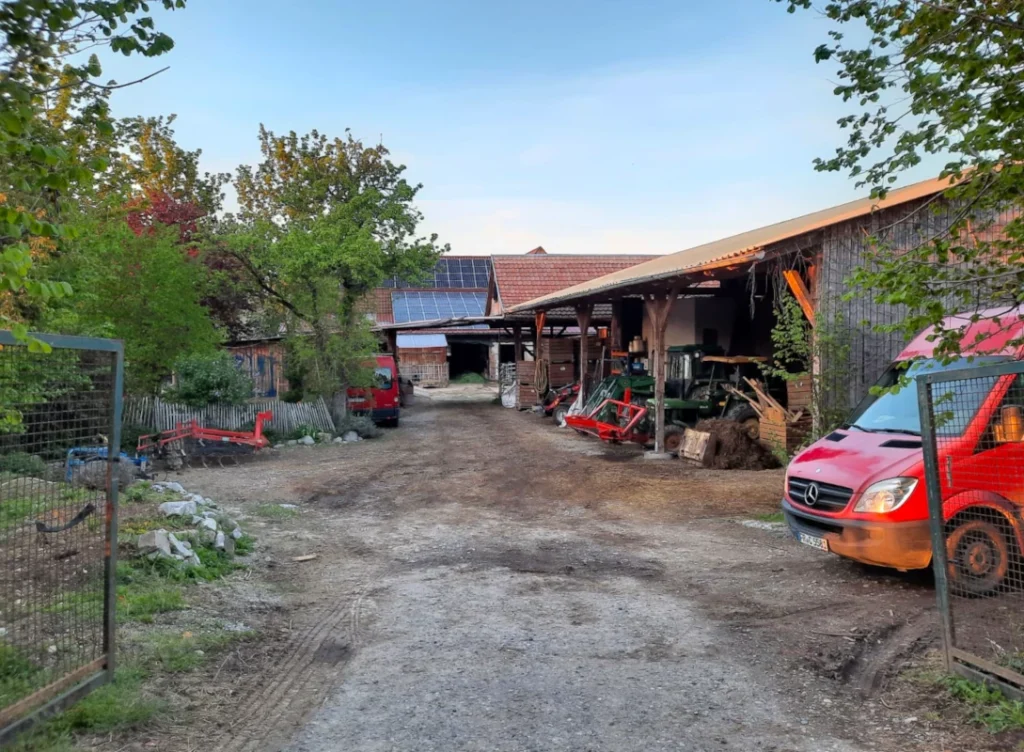 Einblick in die Landwirtschaft: Der offene Hofbereich des Luzernenhofs mit Scheunen, Traktoren und Solaranlagen im Abendlicht – hier entstehen regionale Lebensmittel.