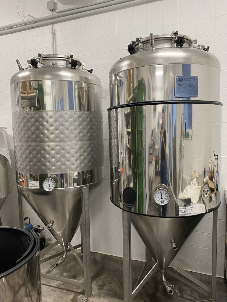 Zwei große, glänzende Edelstahl-Gärtanks in der hell gefliesten Produktionsstätte von St. Ferment.
