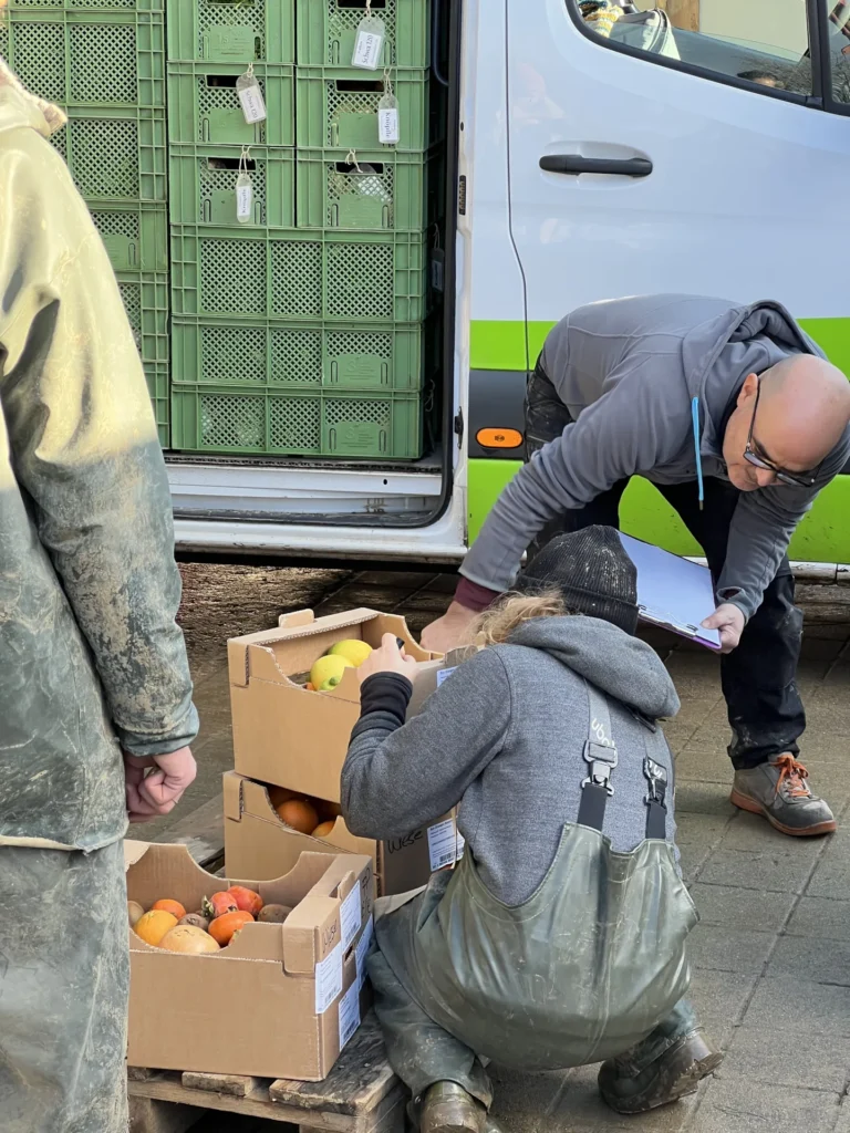 Sorgfalt bei der Übergabe: Genaue Prüfung der Lieferscheine und der Ware (Orangen und Kakis) durch Landwirte und Fahrer direkt bei der Ankunft auf dem Hof.
